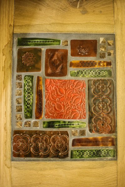 Detail keramickej mozaiky od Inky na sedení pri peci